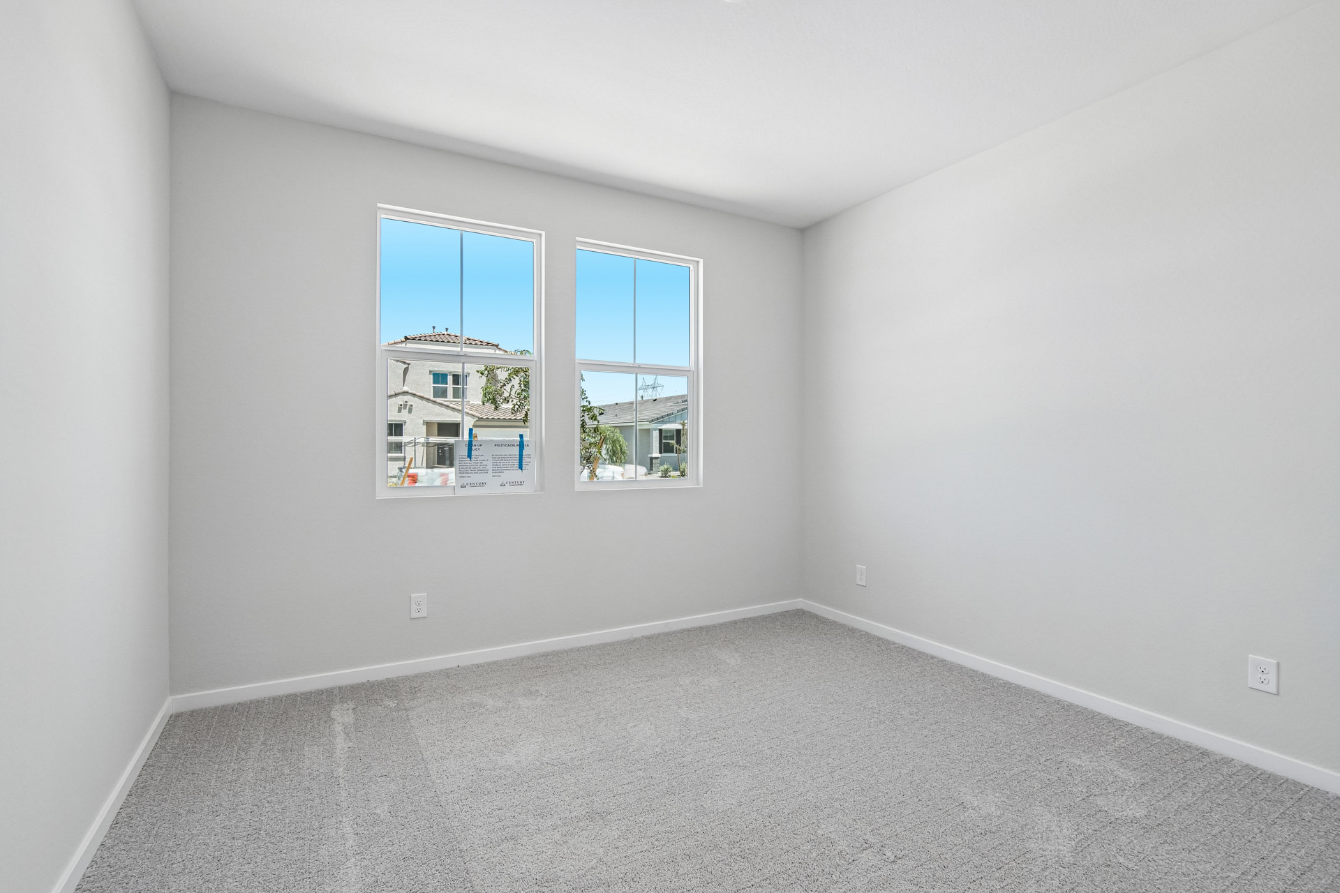 A room with a window and a white wall with a picture of a house.