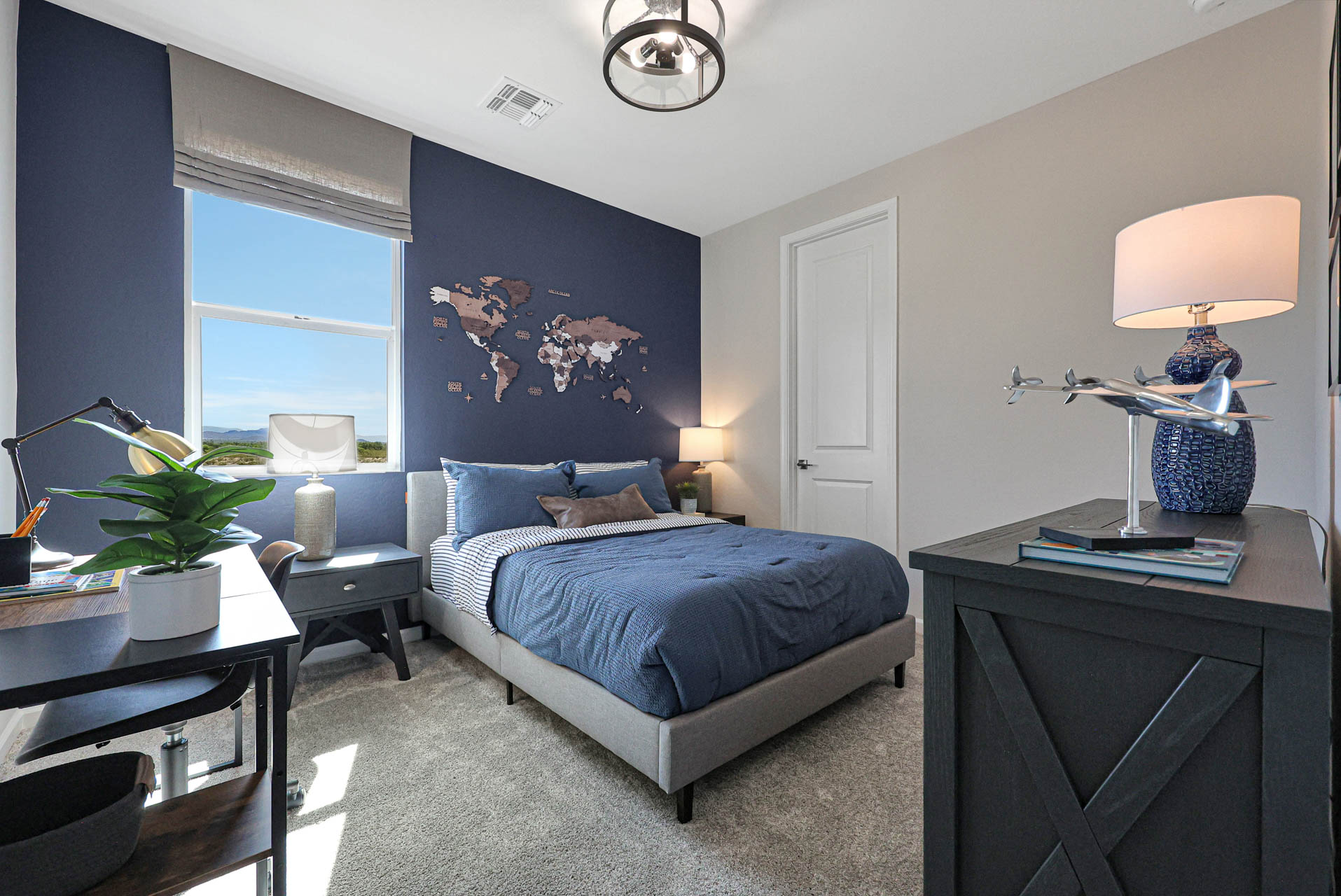 A bedroom with a bed desk and a window.