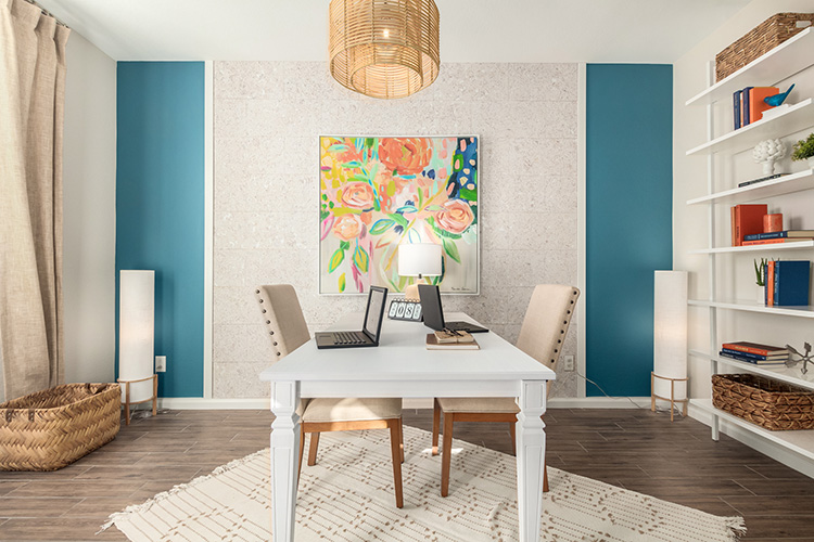 A room with a table and a lamp and a painting on the wall.