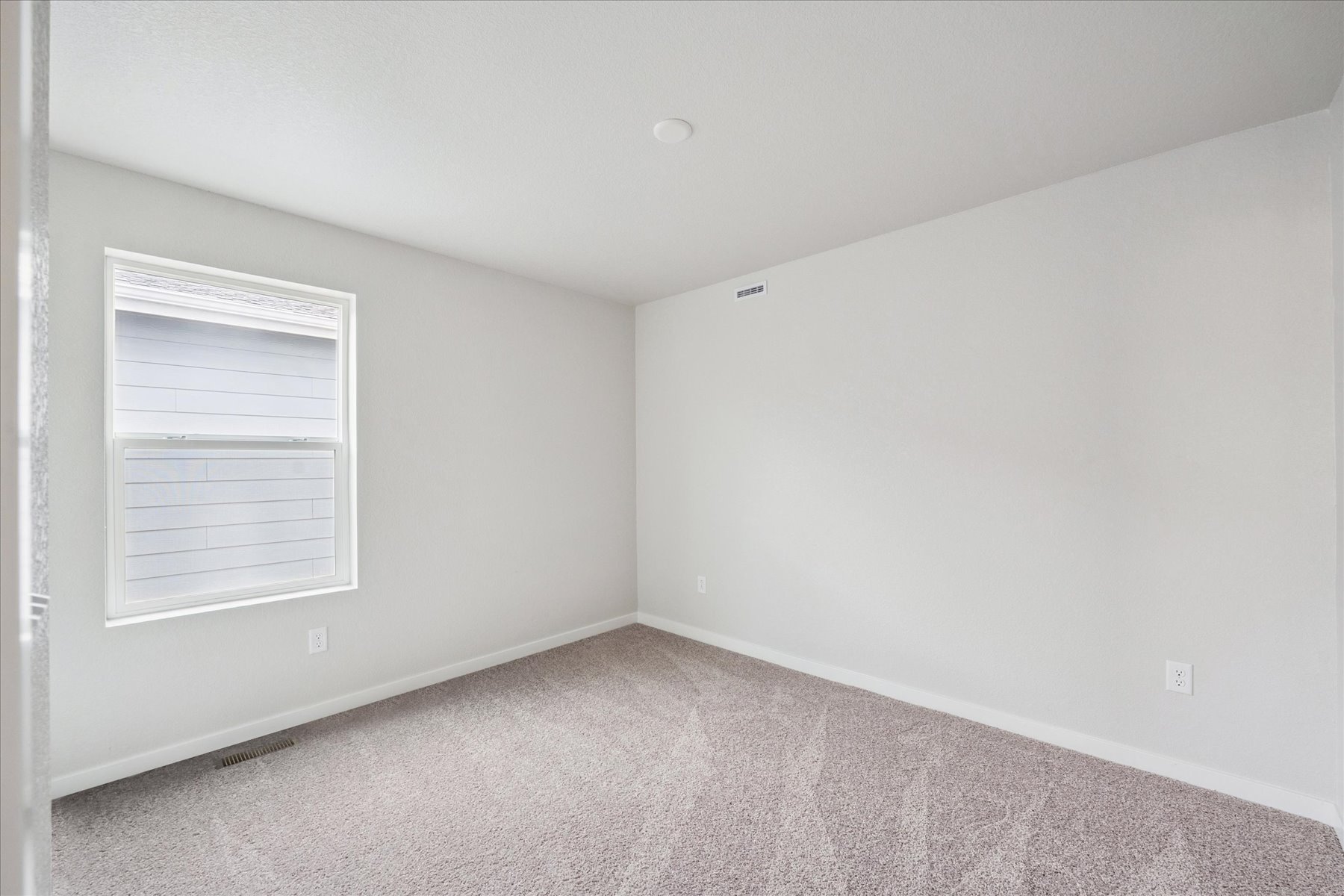 A room with a white wall and a window.