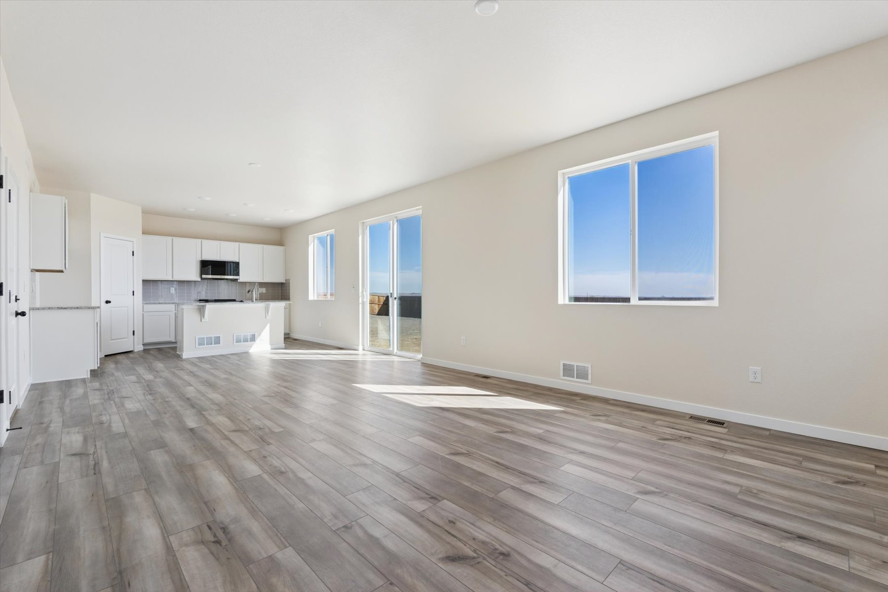 A large empty room with a wood floor and white cabinets.