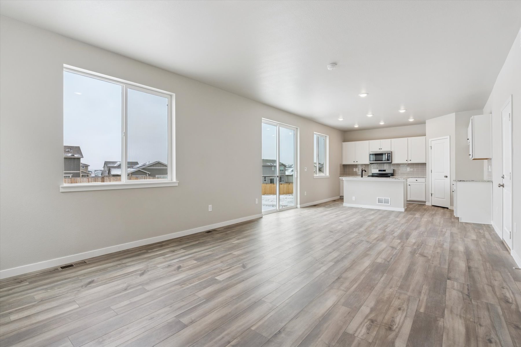 A large empty room with a wood floor and white cabinets.