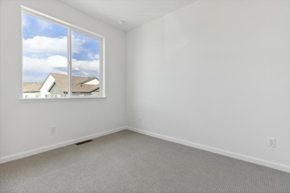 A room with a window and a white wall.