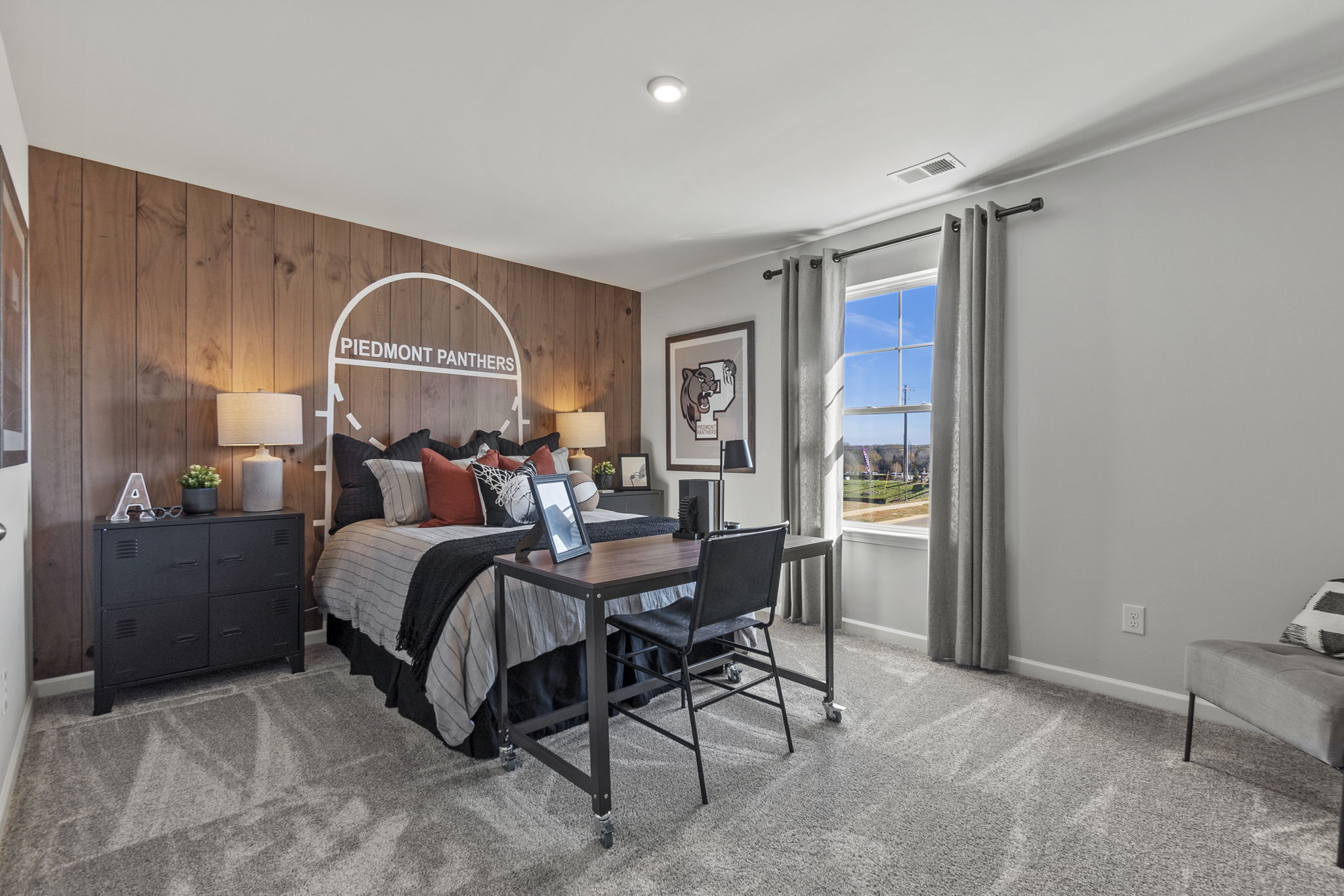 A bedroom with a bed desk and a chair.