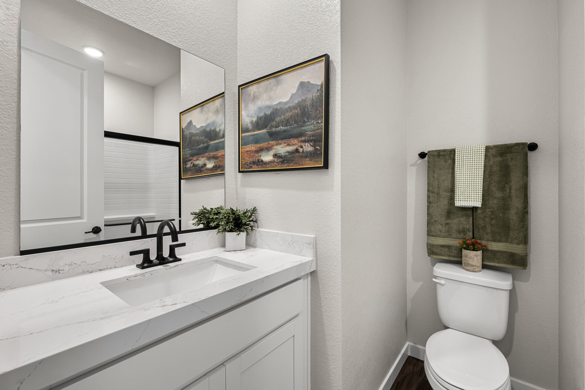 A bathroom with a sink toilet and a mirror.