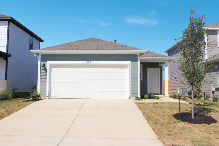 A one-story house with garages and a tree.
