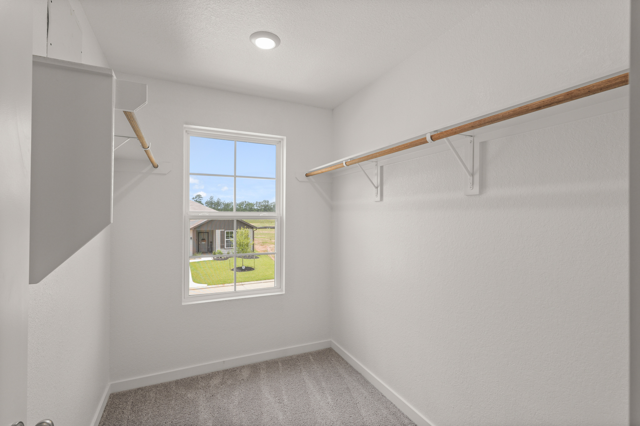 A room with a window and a carpeted floor.