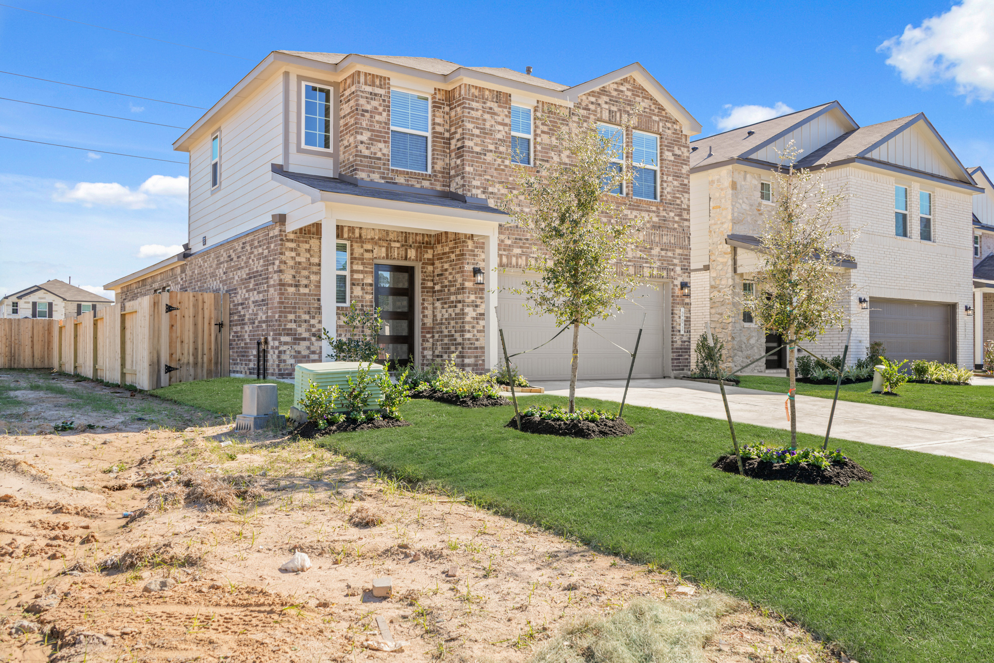 A large brick house with trees and grass in front of it.