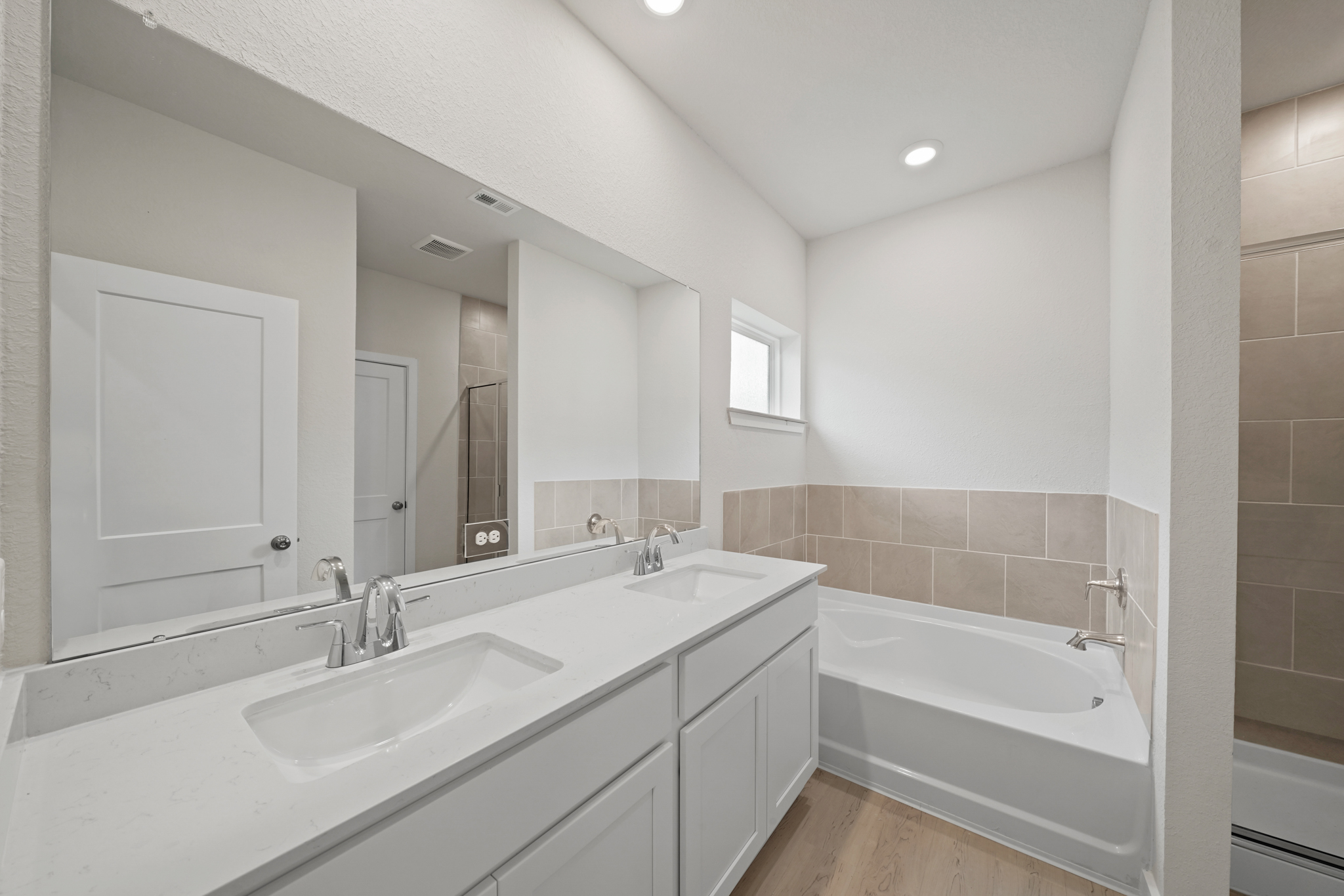 A bathroom with a tub sink and mirror.
