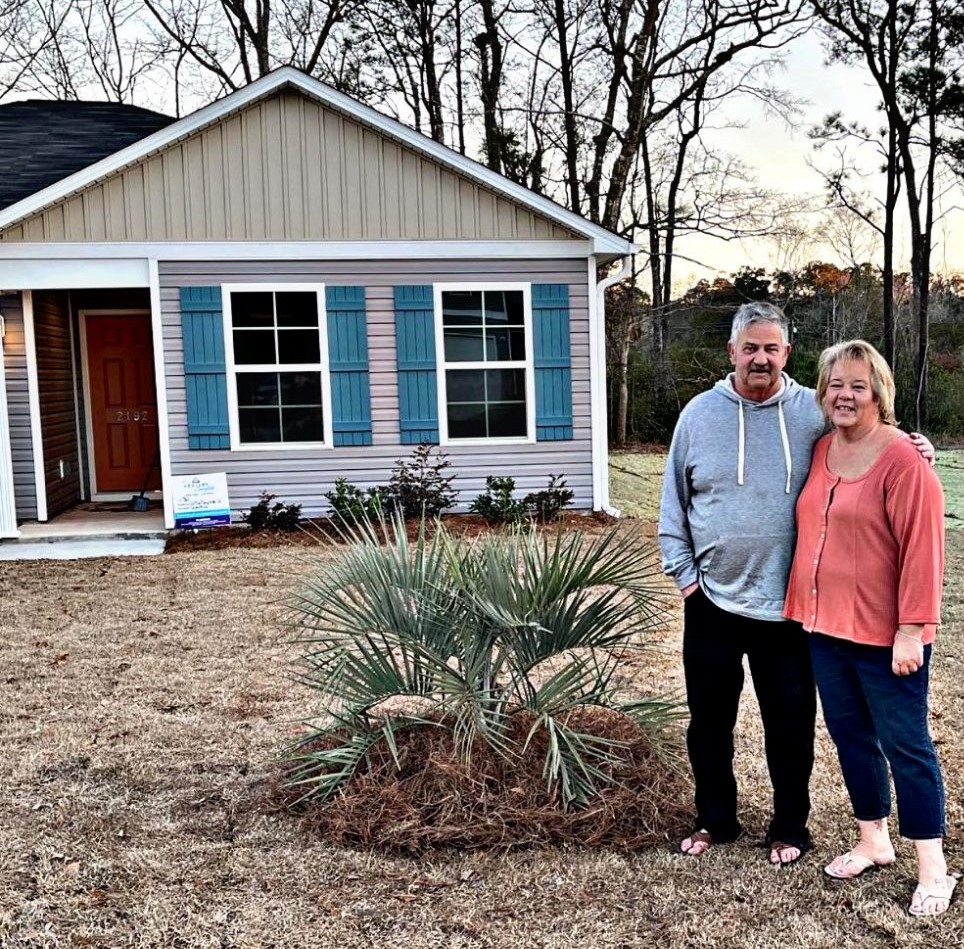 A man and woman standing in front of a house.